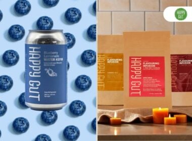 A can of blueberry lemonade water kefir on a background of blueberries is on the left; on the right are three Happy Gut flavouring infusion packs displayed with candles and a warm-toned background.