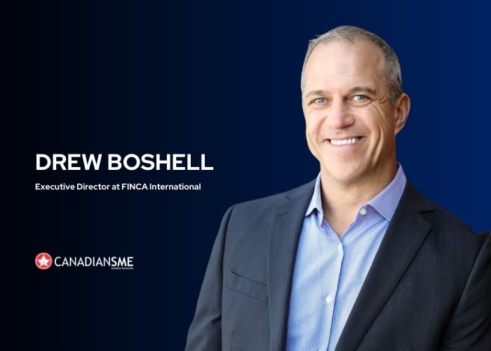 A man in a blue suit and light blue shirt smiles in front of a blue gradient background. Text reads: Drew Boshell, Executive Director at FINCA International. The Canadians SME logo appears in the lower left corner.