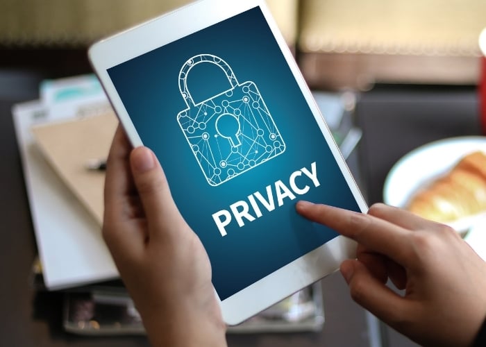 A person holds a tablet displaying an image of a padlock with the word PRIVACY on the screen, symbolizing digital security and online privacy protection.