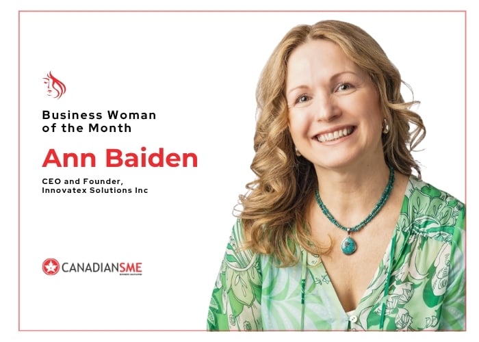 A smiling woman with wavy blonde hair wearing a green patterned blouse and a turquoise necklace is featured next to text naming her Ann Baiden, Business Woman of the Month for CanadianSME.