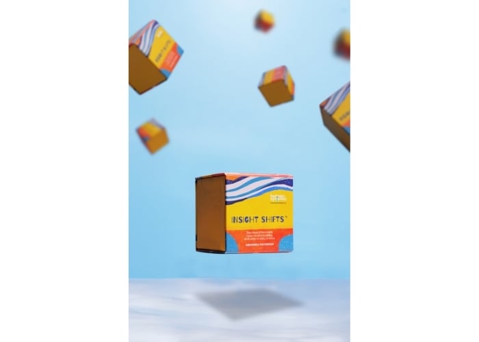 A colorful box labeled Insight Shifts floats midair against a blue sky, surrounded by several similar boxes in the background, creating a surreal, weightless effect.