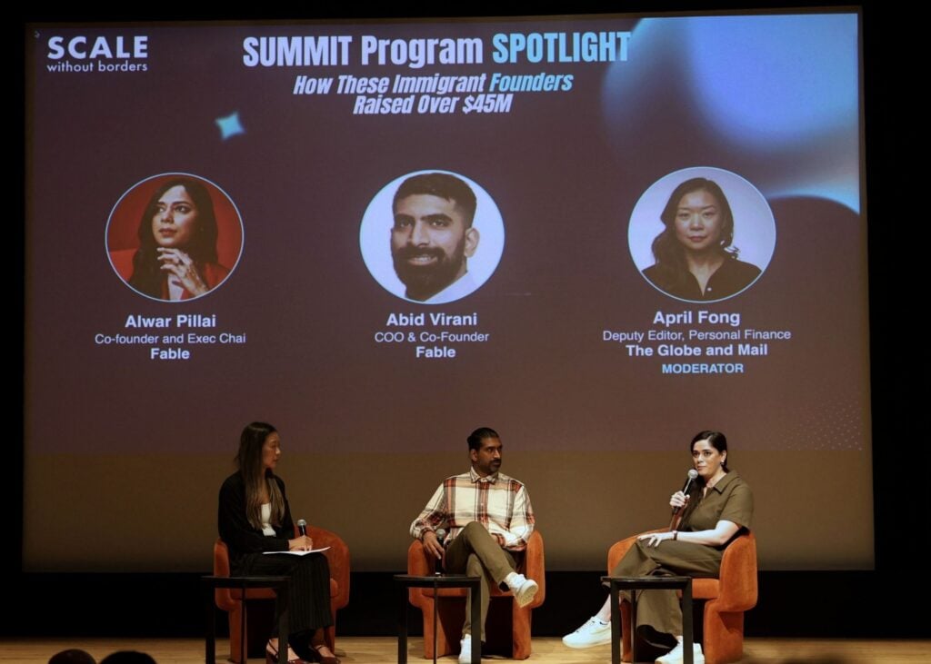 Three speakers and a moderator sit onstage in front of a large screen displaying their names and titles at the SUMMIT Program SPOTLIGHT event by Scale Without Borders.